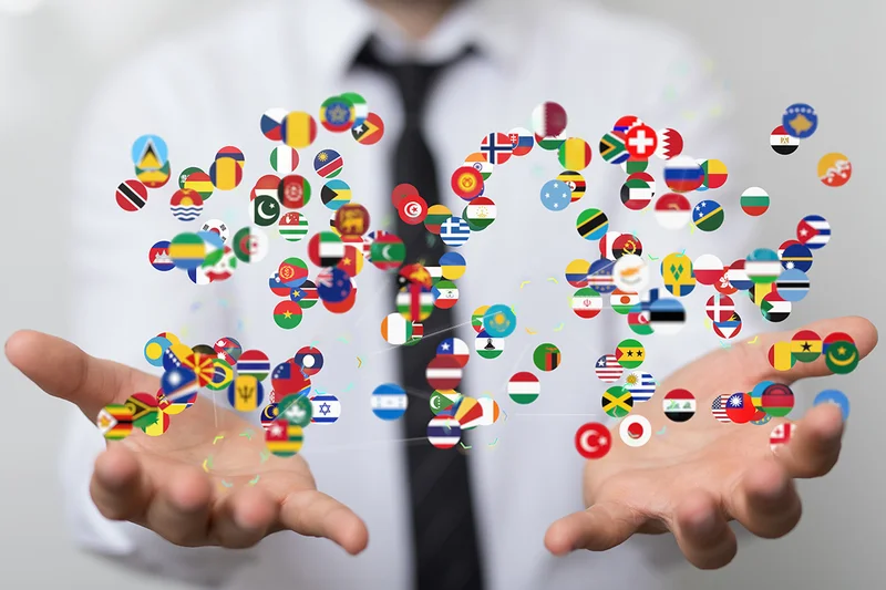 Lokalisierungsmanagement mit eDok – sprachsensibel, effizient, global einsatzbereit Offene Hände mit schwebenden Flaggen – Symbol für weltweite Lokalisierung und Übersetzung