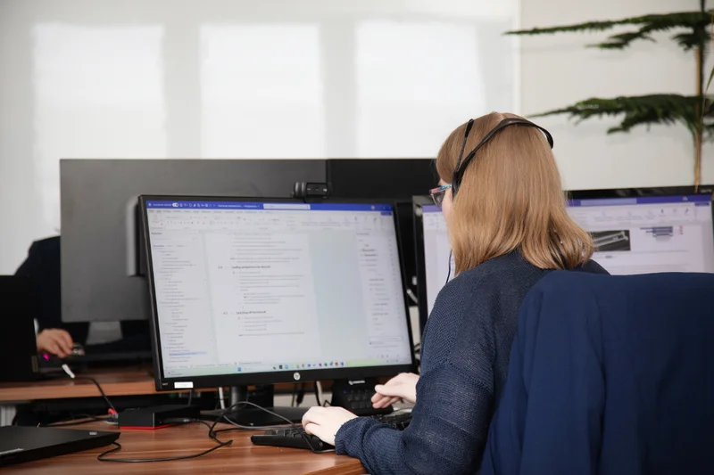 Strukturierte Softwaredokumentation bei eDok – klar, effizient, anwenderfreundlich Technische Redakteurin arbeitet an Softwaredokumentation mit zwei Monitoren und Headset